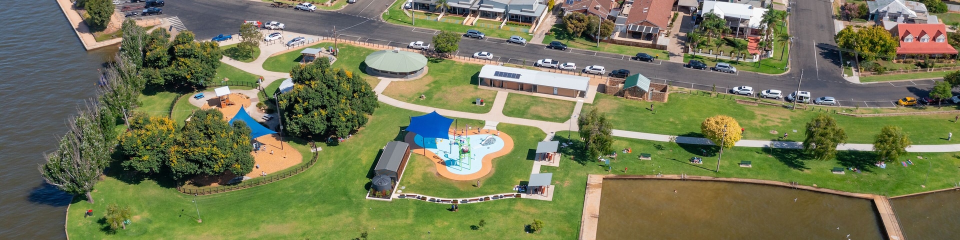 An aerial view of a residential area with houses, a park, and a body of water.