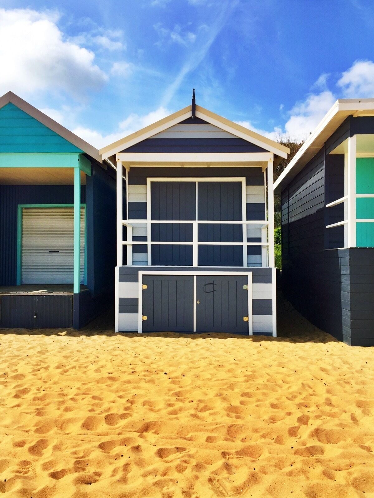 Uma fileira de casas de praia com uma praia de areia em frente.