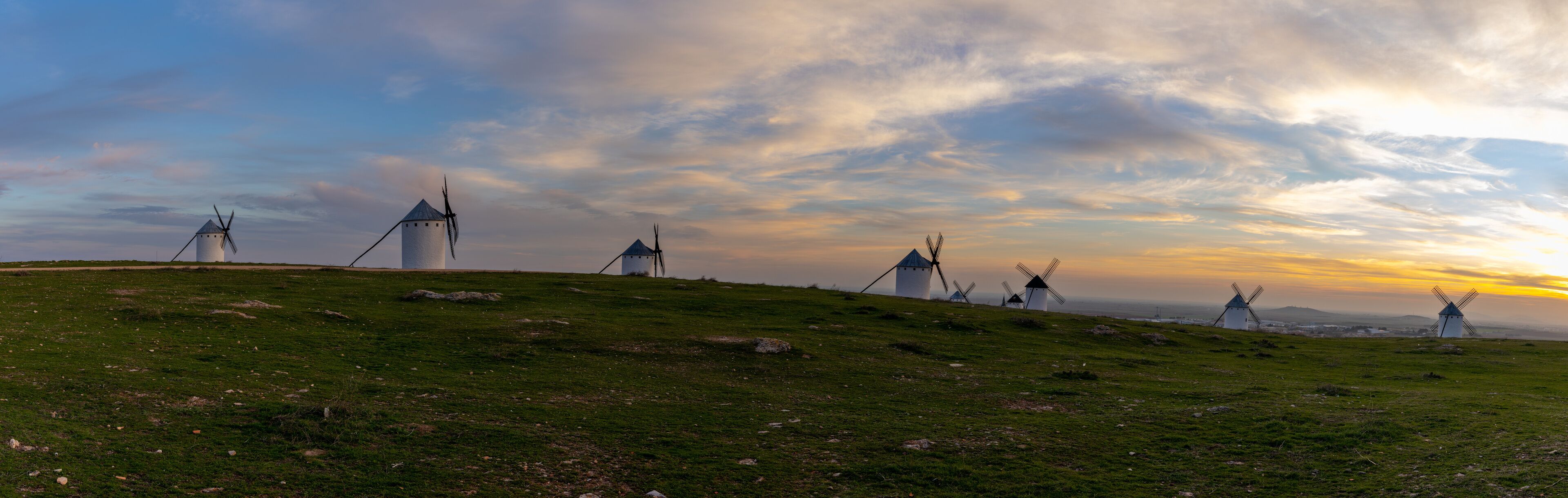 panorama view of the historic white windmills of La Mancha above the town of Campo de Criptana at sunset