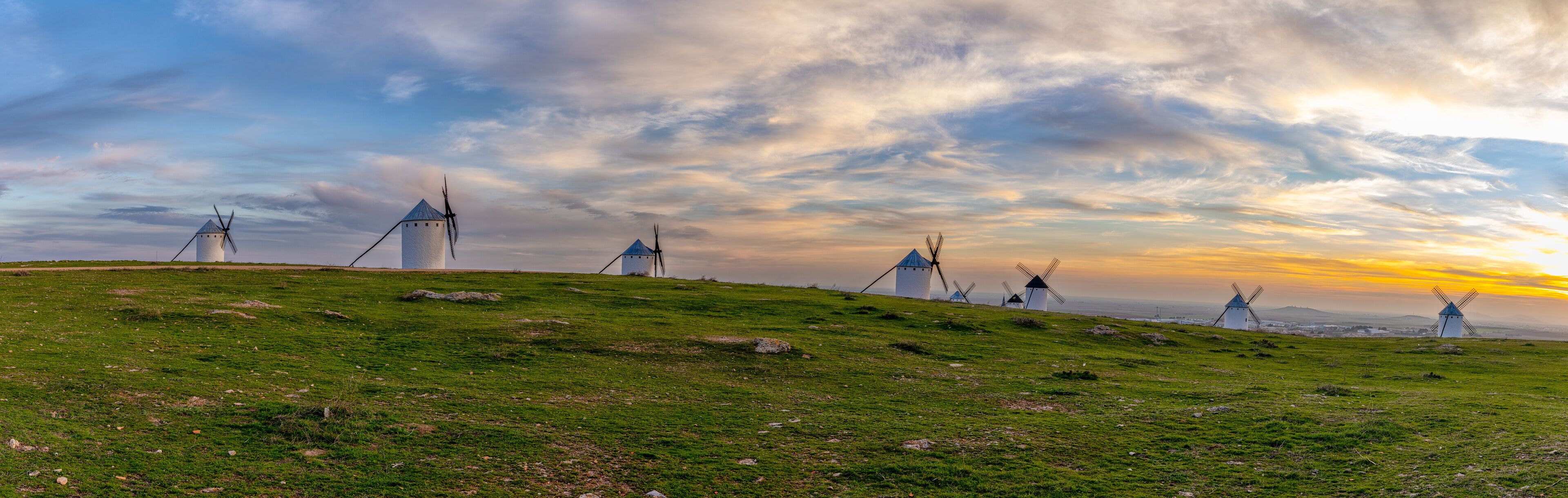 panorama view of the historic white windmills of La Mancha above the town of Campo de Criptana at sunset