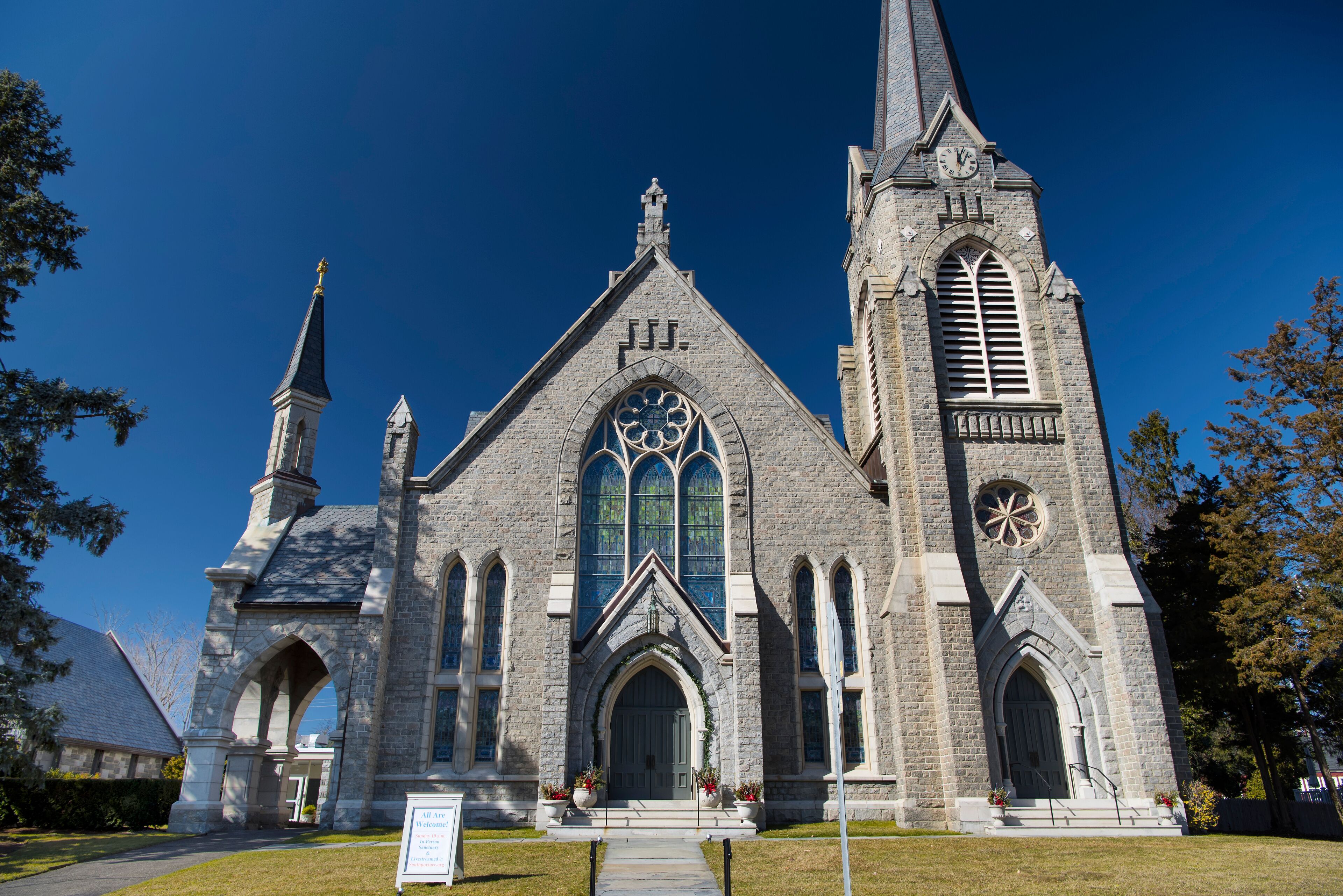 A Gothic-style church with a tall steeple, large arched windows, and a clock tower.