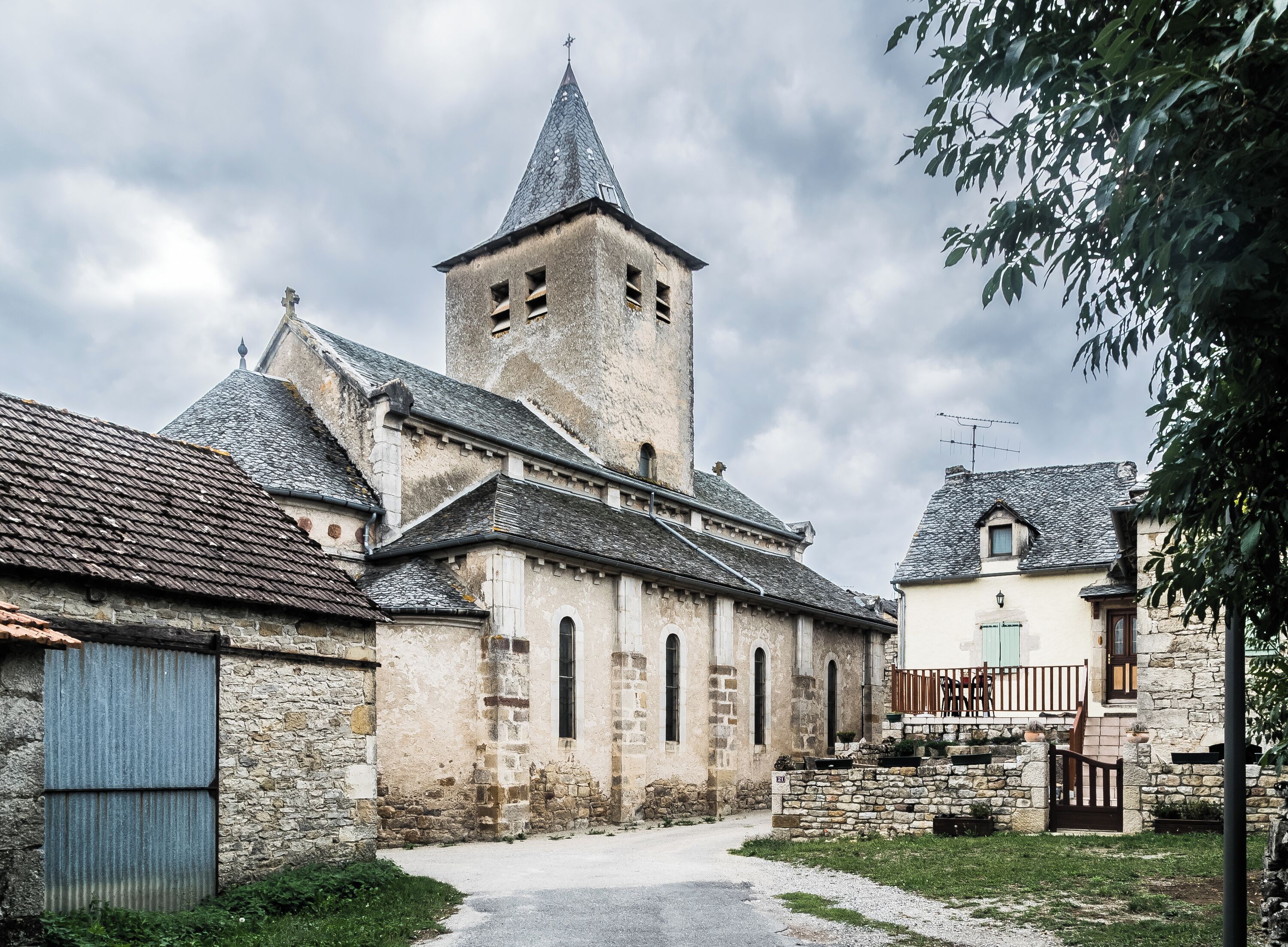 A historic church with a tall bell tower and a stone building with a sloped roof.