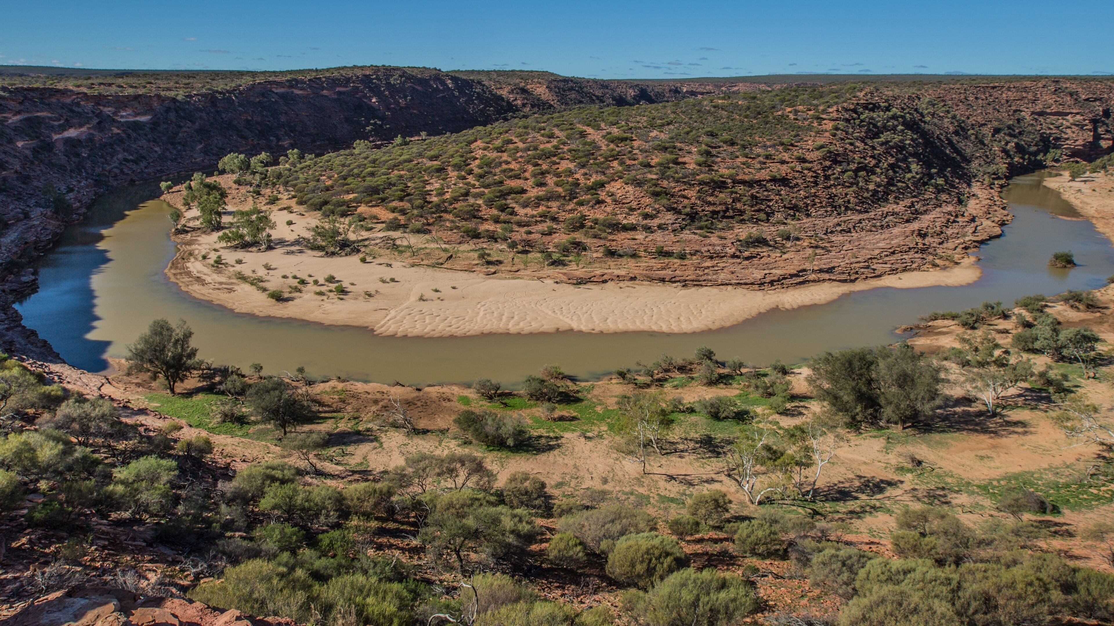 A river winding through a dry, rocky landscape with sparse vegetation.