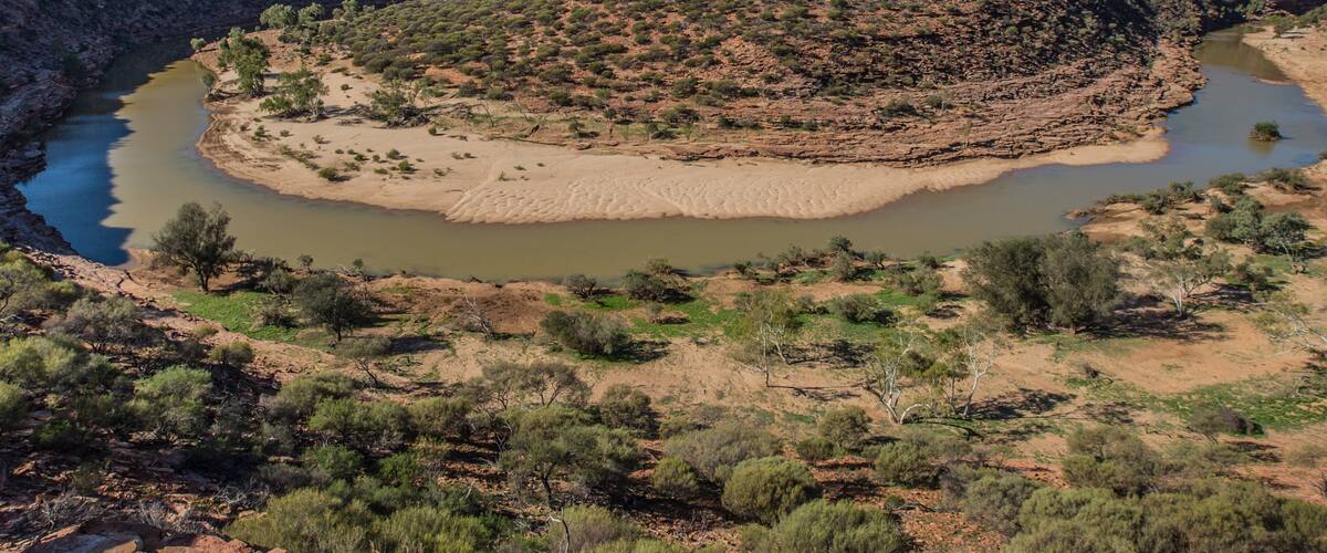 A river winding through a dry, rocky landscape with sparse vegetation.