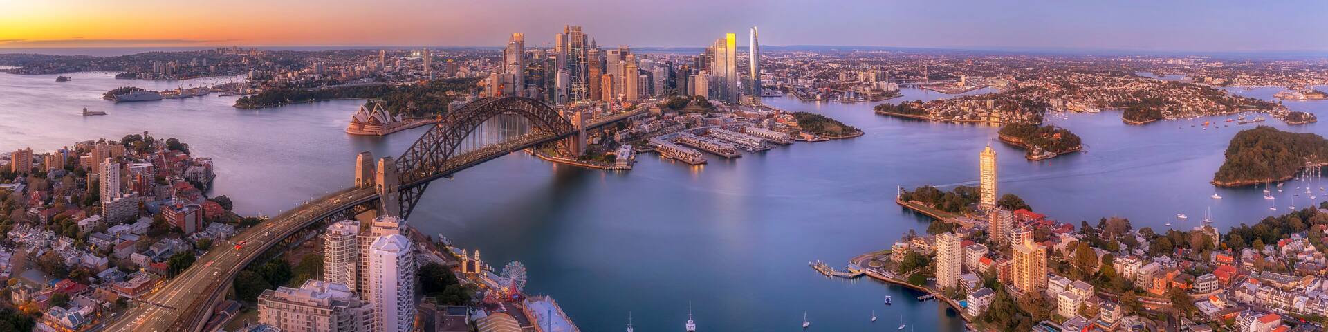 A cityscape with a prominent bridge, a large body of water, and a skyline with high-rise buildings.