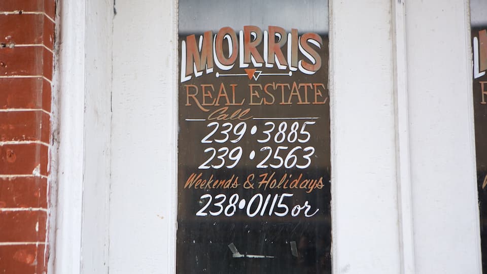 A real estate sign for Morris Real Estate with contact numbers.