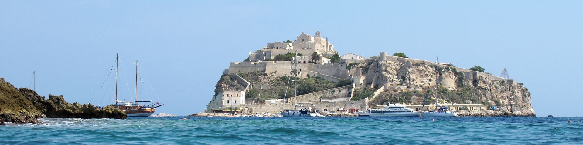 Un pueblo costero con un castillo imponente en un acantilado con vistas al mar.
