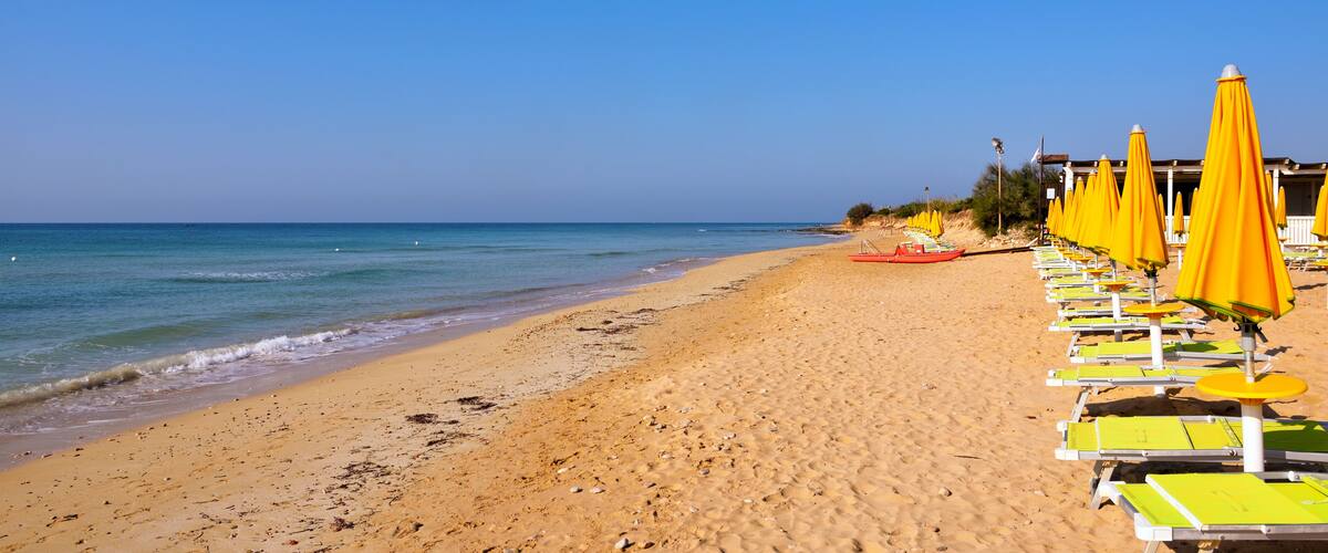 A sandy beach with yellow umbrellas and lounge chairs.