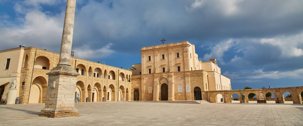 A historical building with arches and a tall column in front.