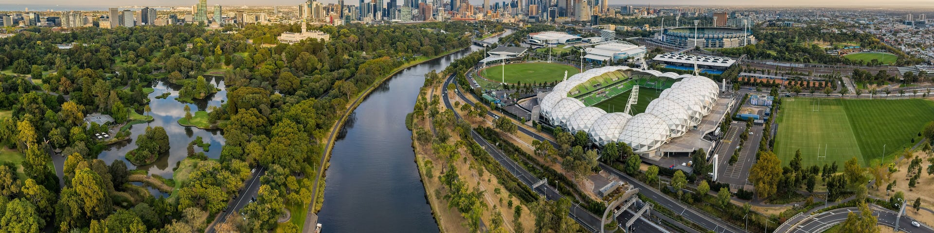 Aerial panoramic dawn view of the MCG and AAMI stadium, with the CBD in the background