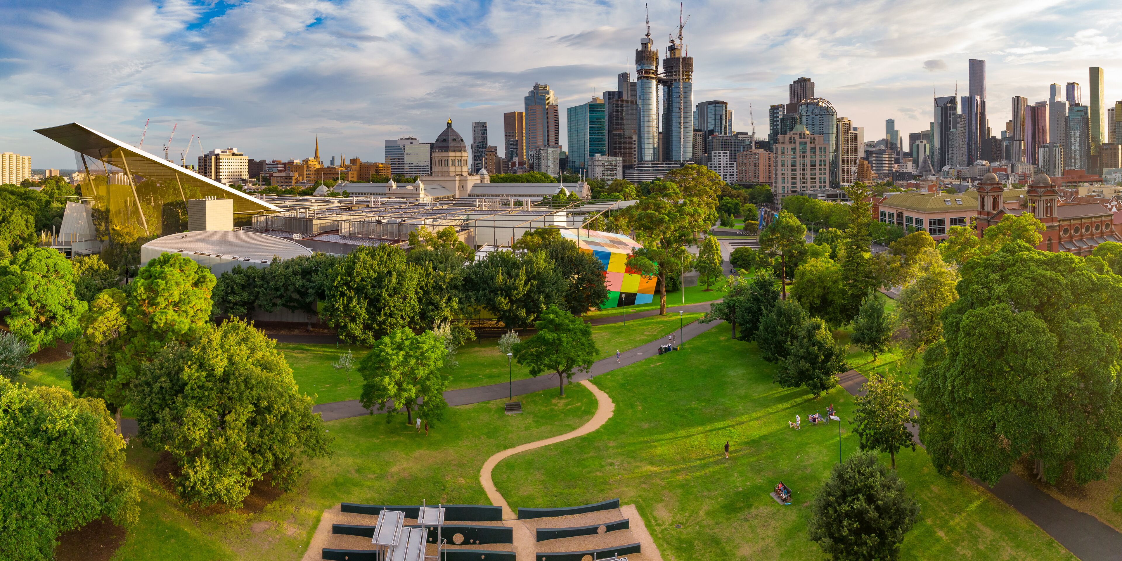Aerial view of a green inner city park with a city skyline behind