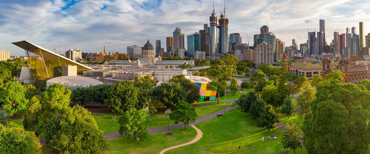 Aerial view of a green inner city park with a city skyline behind