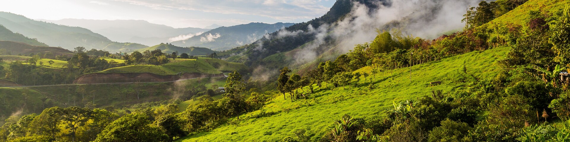 Un valle verde exuberante con colinas ondulantes, una montaña al fondo y un pequeño pueblo ubicado entre los árboles.