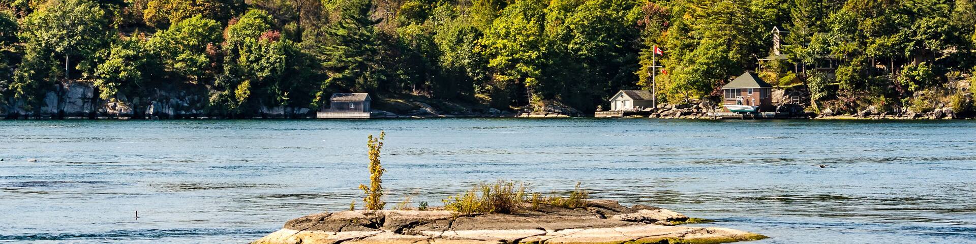 Tiny Island in the Thousand Islands, St. Lawrence River with cottages in the background