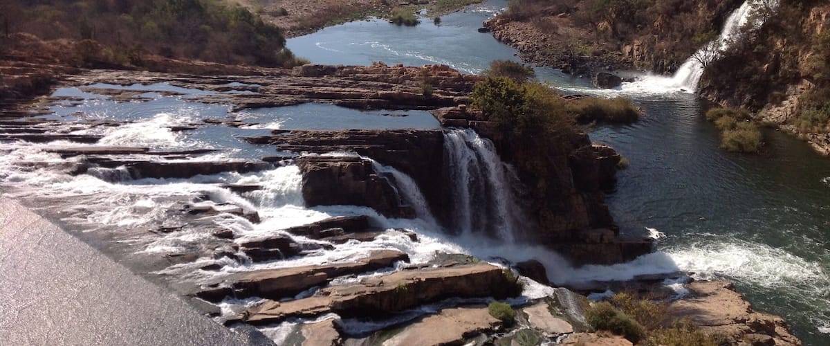 A river flowing through a mountainous landscape with multiple waterfalls.