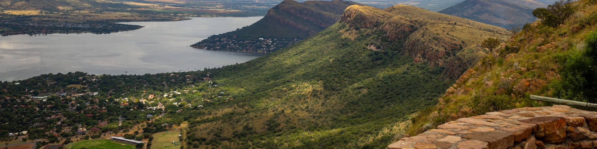 Cuestas, landforms of tilted rock layers or strata, on the north shore of Hartbeespoort dam under a cloudy sky in the Magaliesberg mountain range in North West province in South Africa.