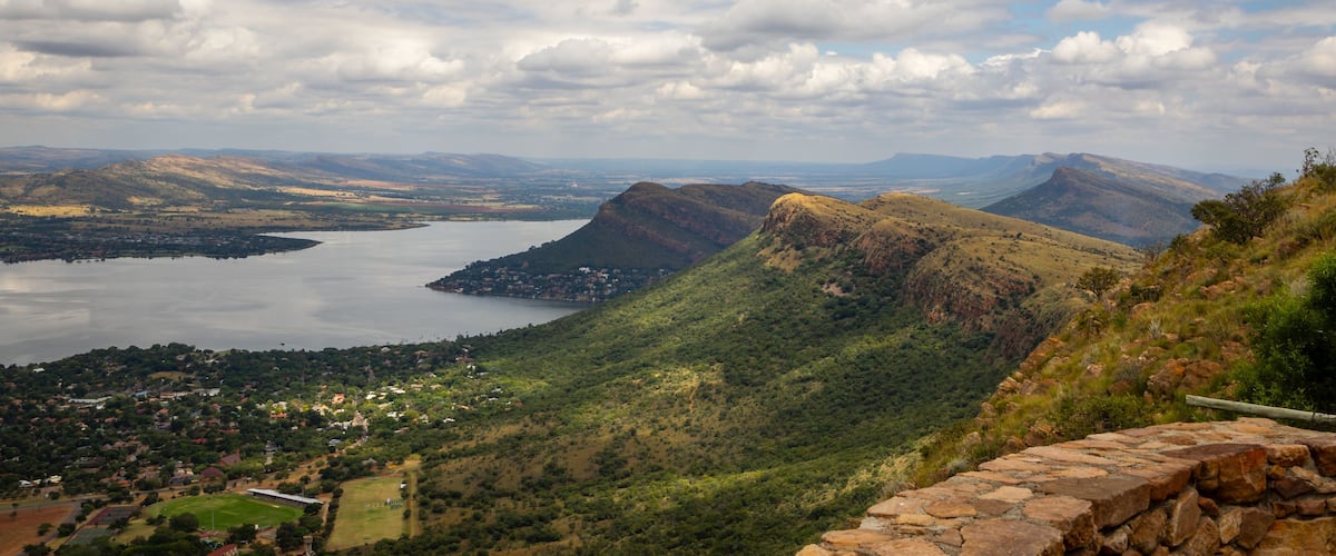 A mountainous landscape with a lake, a town, and a stone wall.
