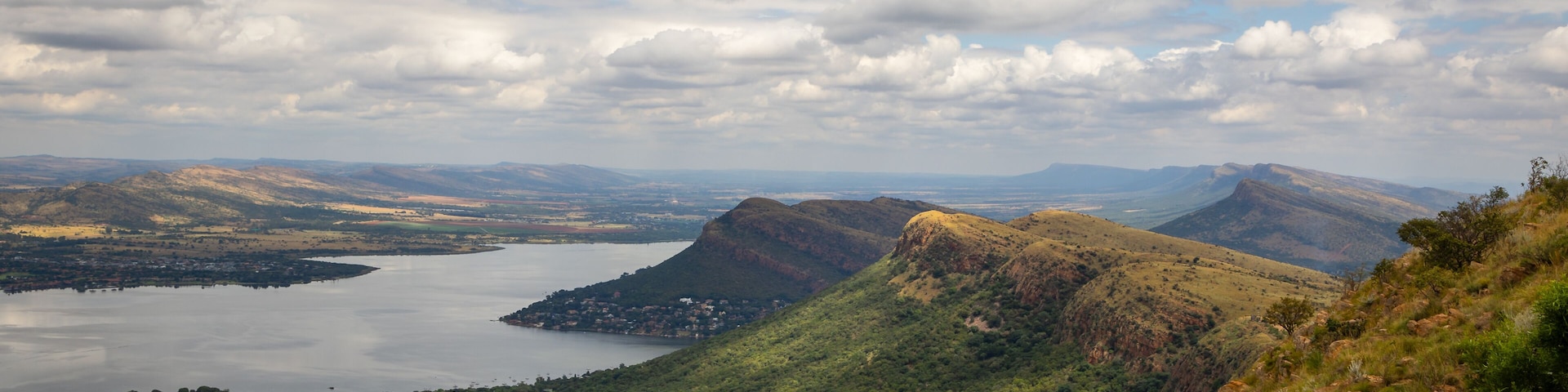 A mountainous landscape with a lake, a town, and a stone wall.