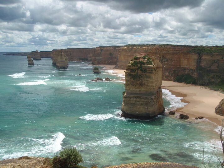 A coastal landscape with prominent rock formations and a sandy beach.
