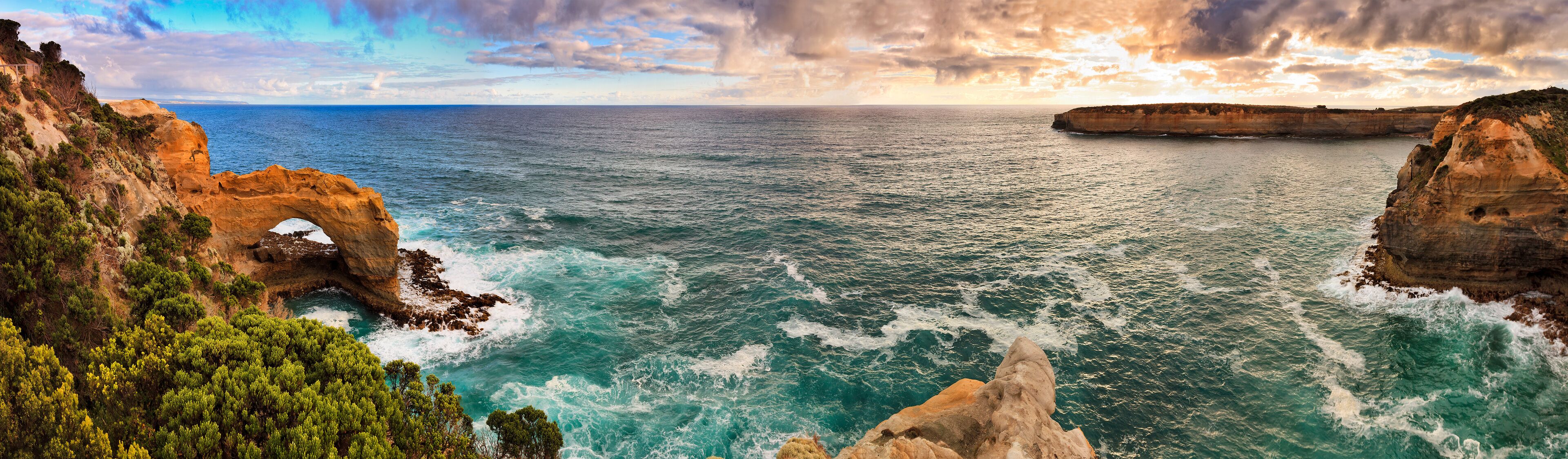 A coastal landscape with cliffs, a sea, and a clear sky.