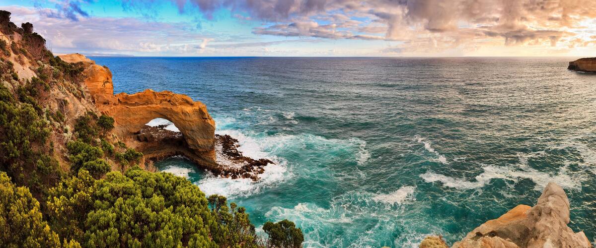 A coastal landscape with cliffs, a sea, and a clear sky.