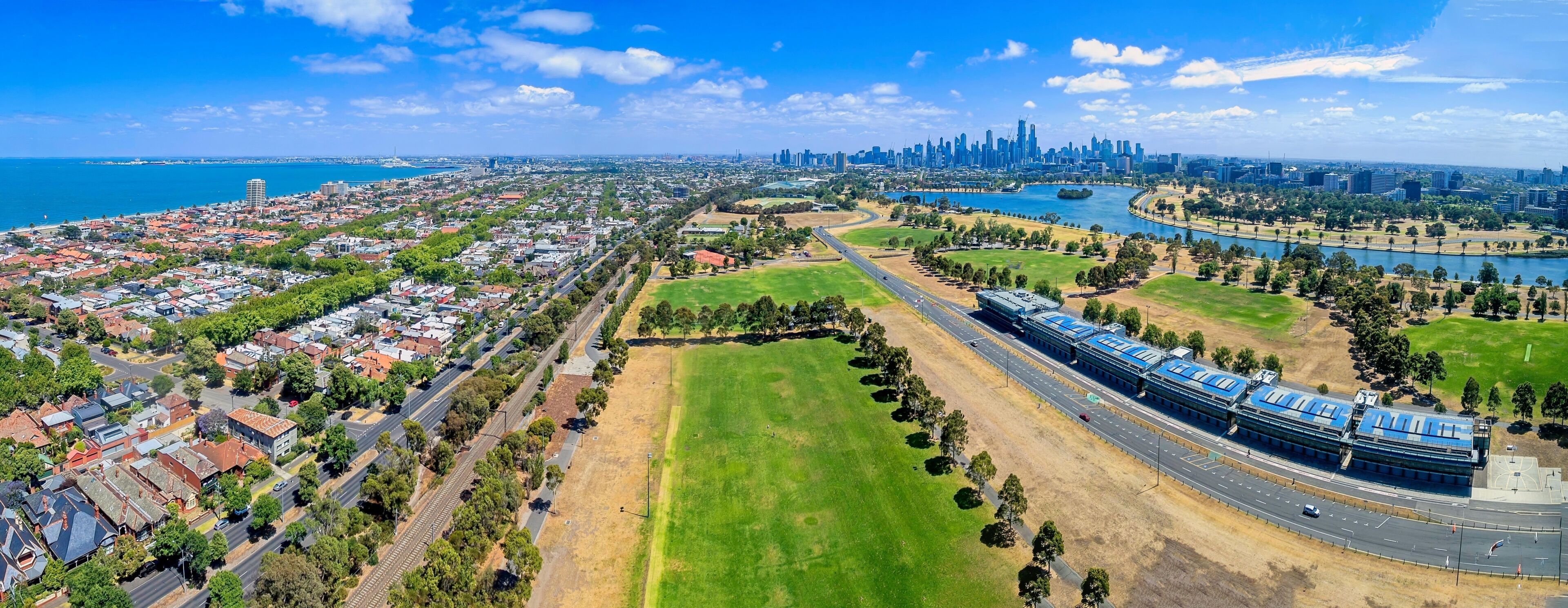 Un paisaje urbano costero con un río, un gran parque verde y una moderna estación de tren.