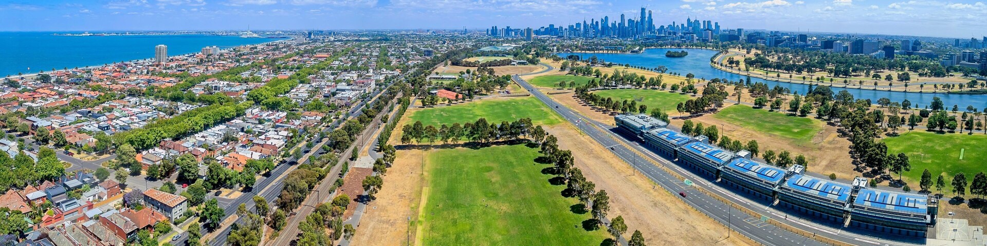 Un paisaje urbano costero con un río, un gran parque verde y una moderna estación de tren.