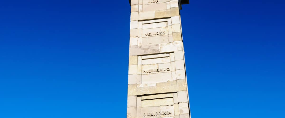 A tall monument with inscriptions and a statue on top.