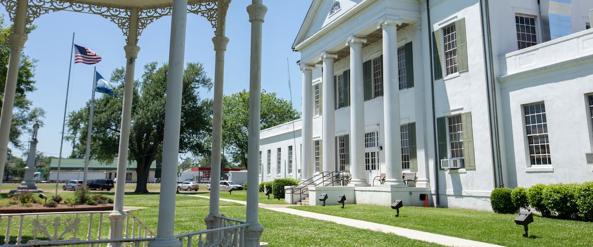 A white building with columns and a flagpole.