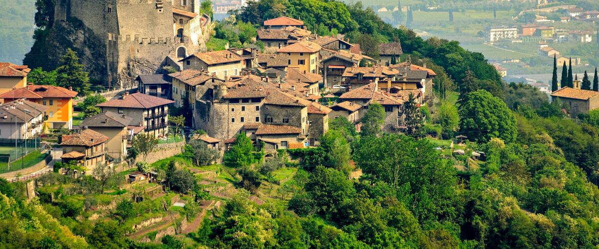 A medieval castle atop a hill overlooking a village with terraced houses.