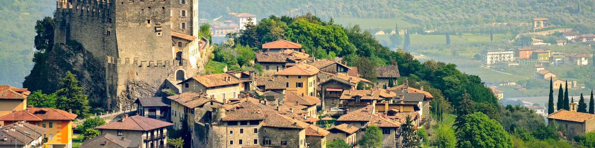 A medieval castle atop a hill overlooking a village with terraced houses.
