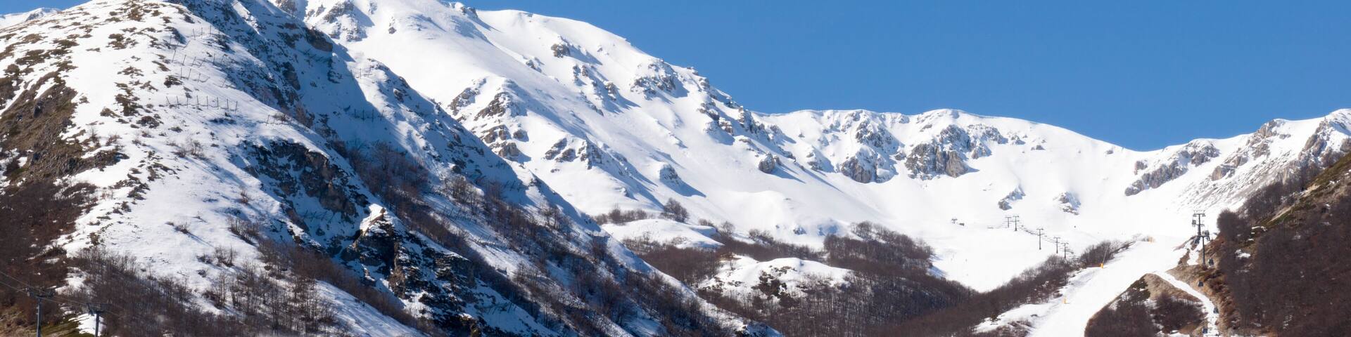 Panorama of a mountainous landscape in winter. The mountain peaks are covered in snow. It's winter, there's a lot of snow and it's a sunny day.