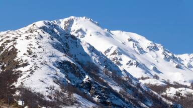 Panorama of a mountainous landscape in winter. The mountain peaks are covered in snow. It's winter, there's a lot of snow and it's a sunny day.