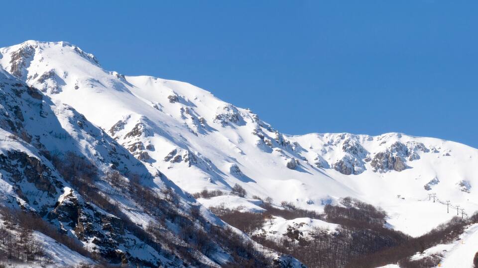 A snow-covered mountain peak with a clear blue sky.
