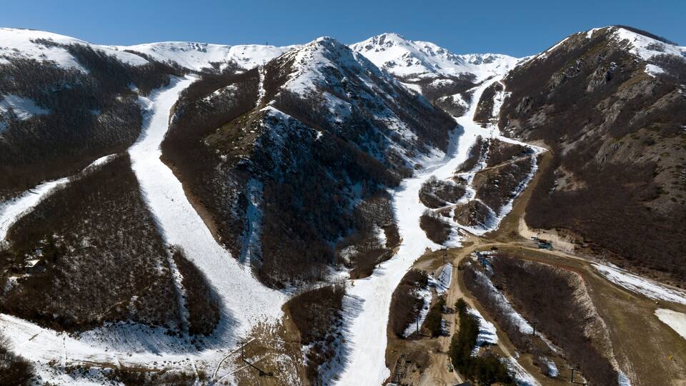 A snow-covered mountain landscape with a ski slope and a dirt road.