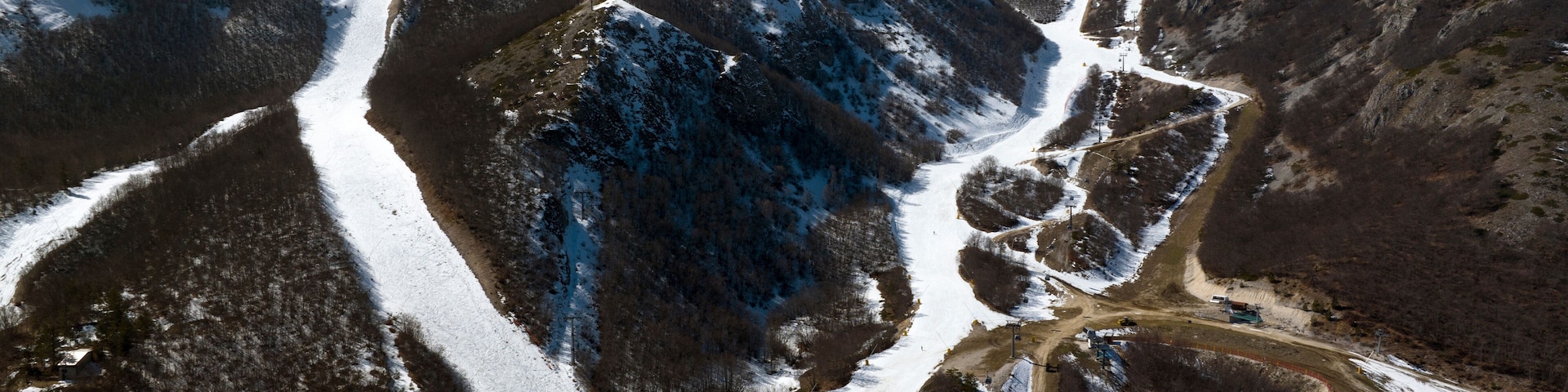 Paisaje nevado de una montaña con una pista de esquí y un camino de tierra.