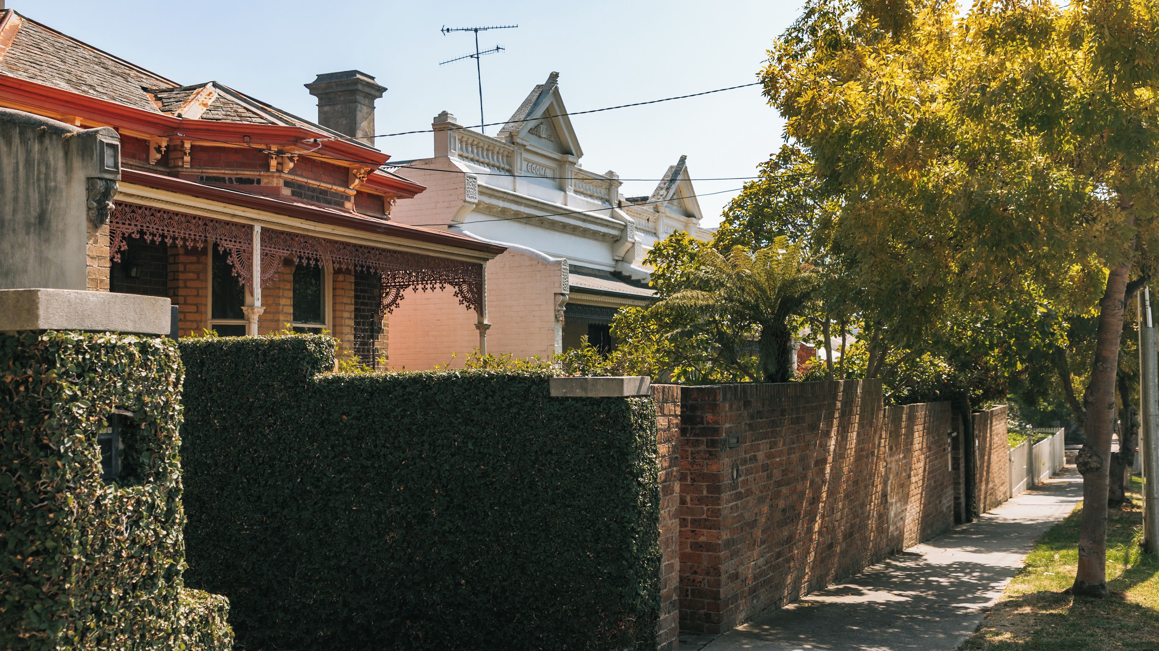 Uma rua residencial com casas de tijolo, um viveiro e uma árvore.