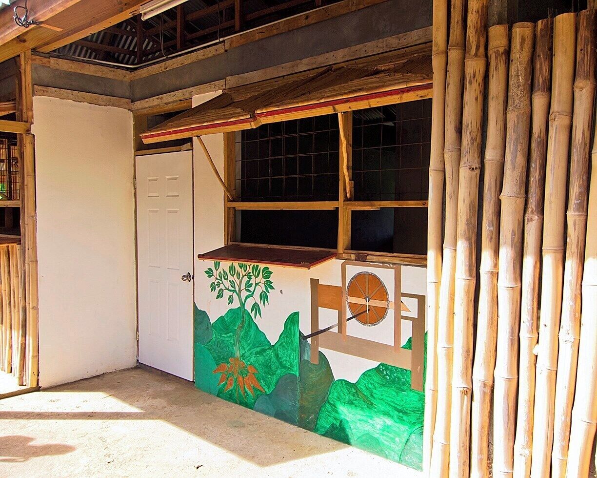 A room with a white door, a window with a grid pattern, and a mural of green mountains and a tree.