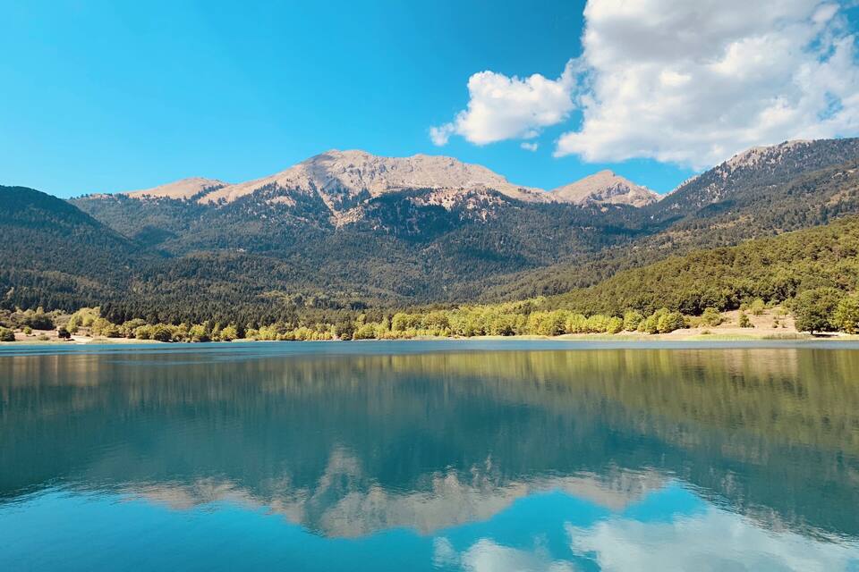 A calm lake reflecting mountains and trees.