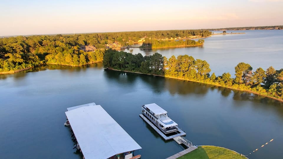 A lake with a dock and a houseboat.