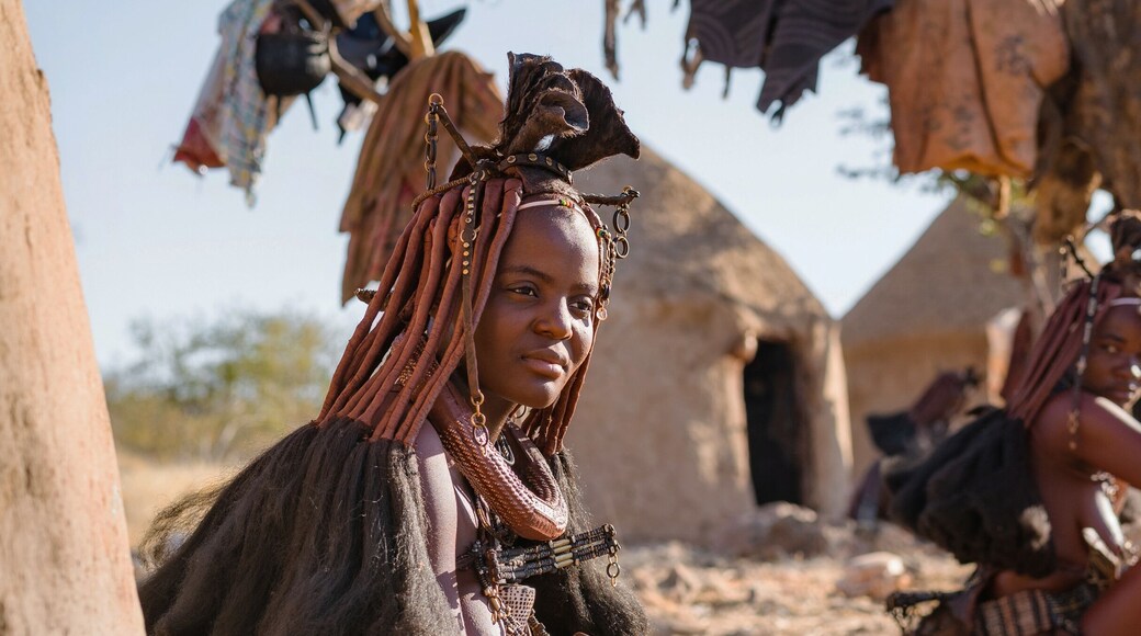 Panoramic shot showing Himba tribeswomen sitting outside their huts in a traditional Himba village near Kamanjab in northern Namibia, Africa.