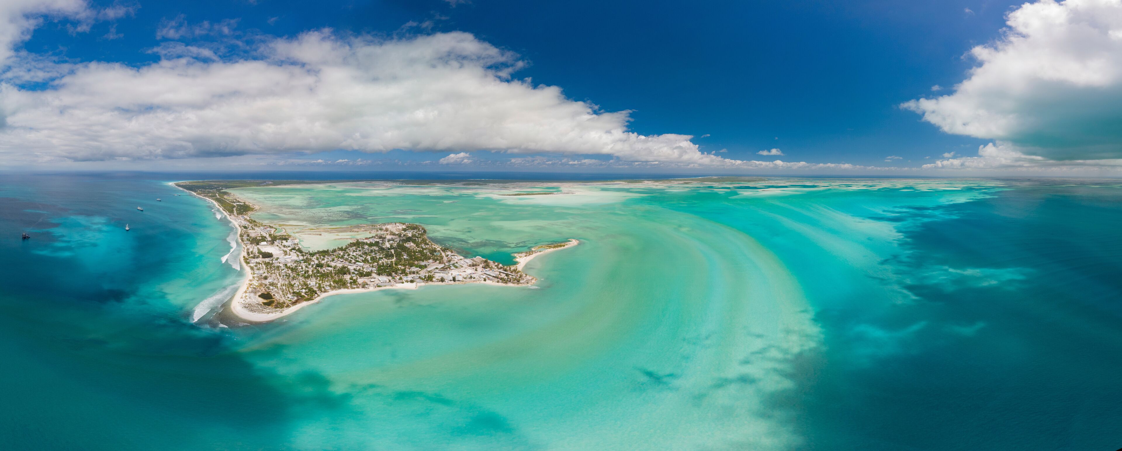 An aerial view of a turquoise island with clear waters and a sandy beach.