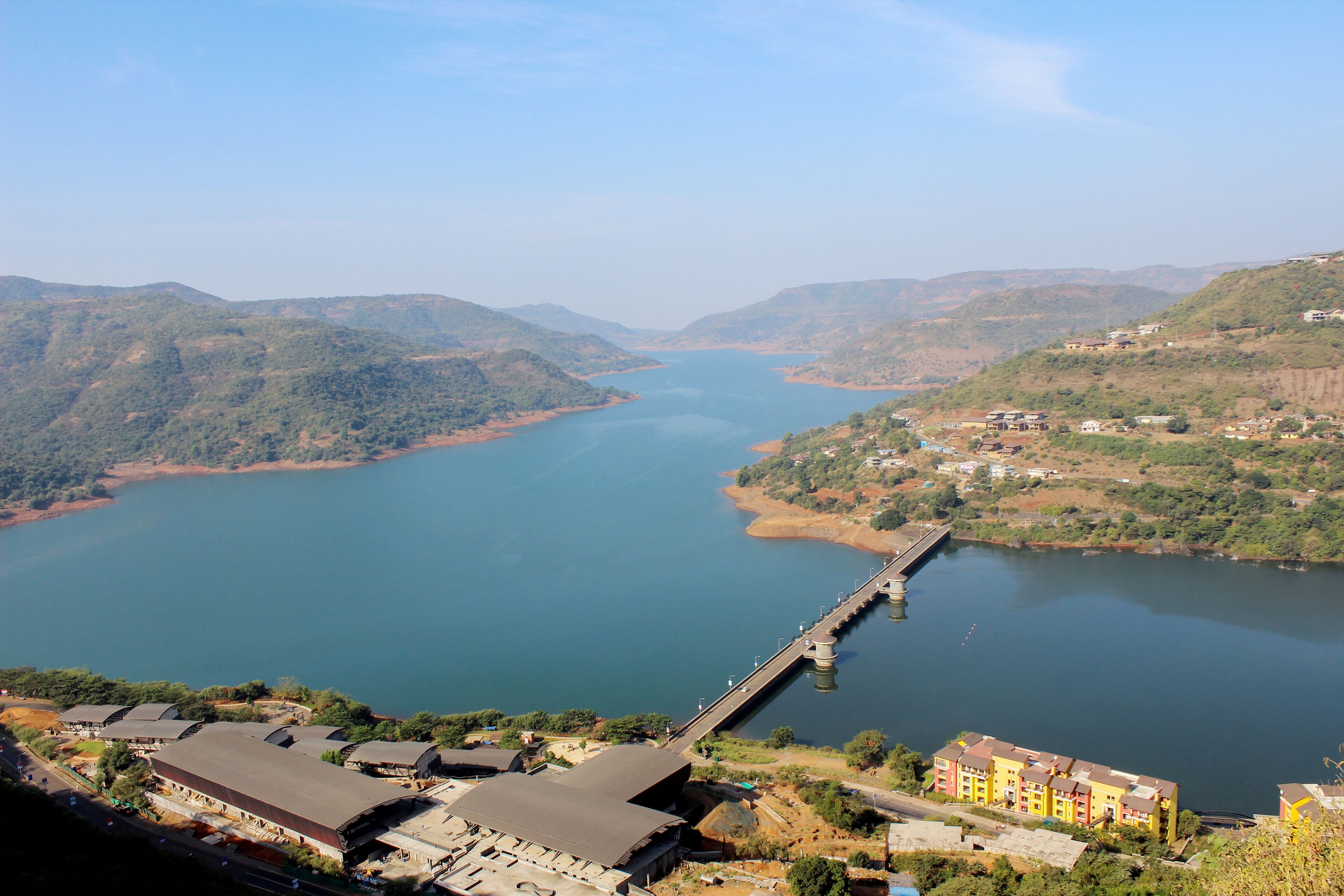 A river with a bridge, surrounded by hills and buildings.