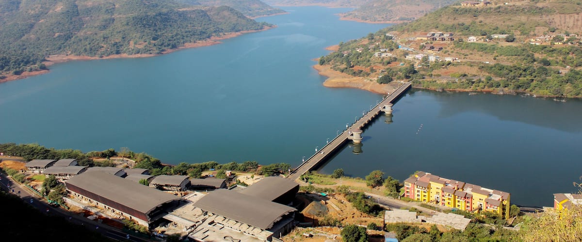 A river with a bridge, surrounded by hills and buildings.