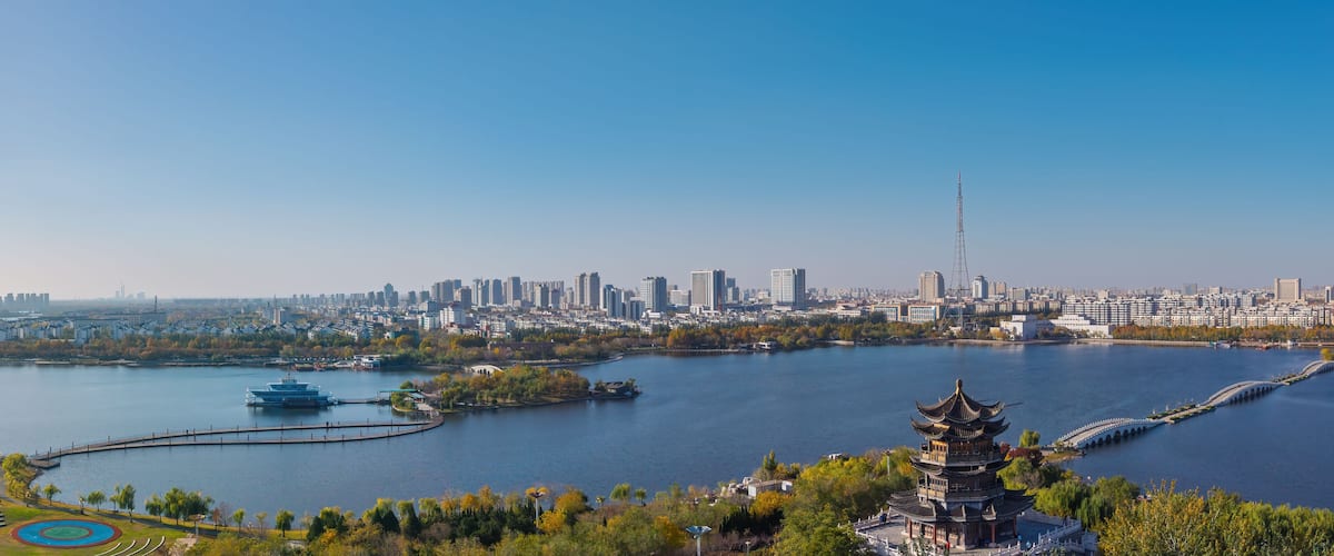 A cityscape with a river, a pagoda, and a modern skyscraper.