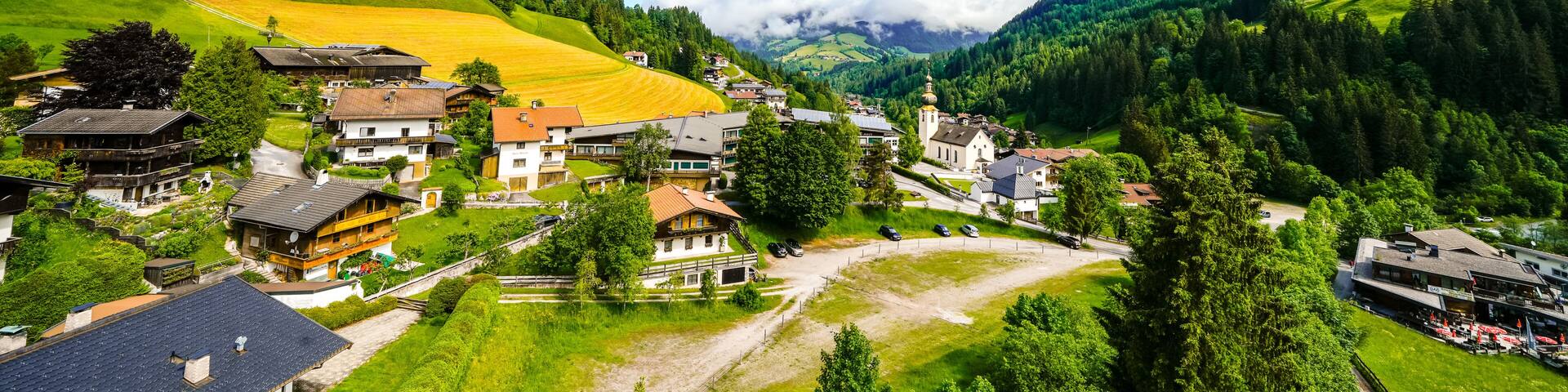 A village nestled in a valley with houses, a church, and a mountain backdrop.