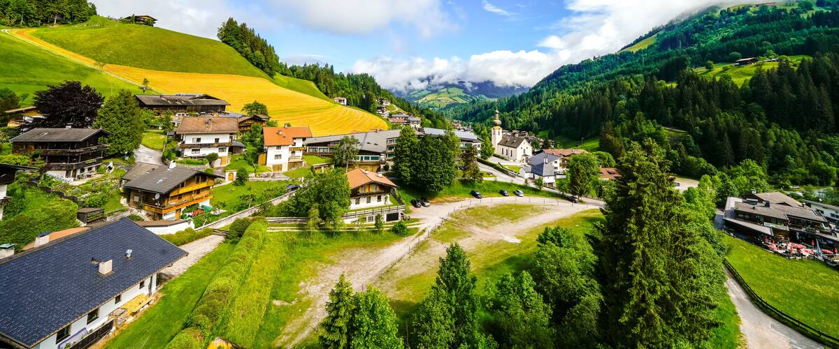 A village nestled in a valley with houses, a church, and a mountain backdrop.
