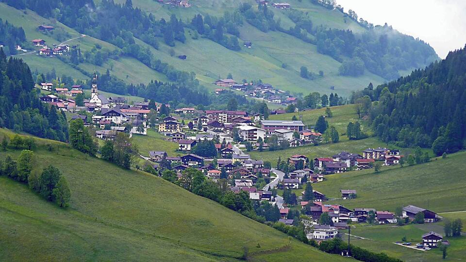 A village nestled in a valley surrounded by hills and forests.