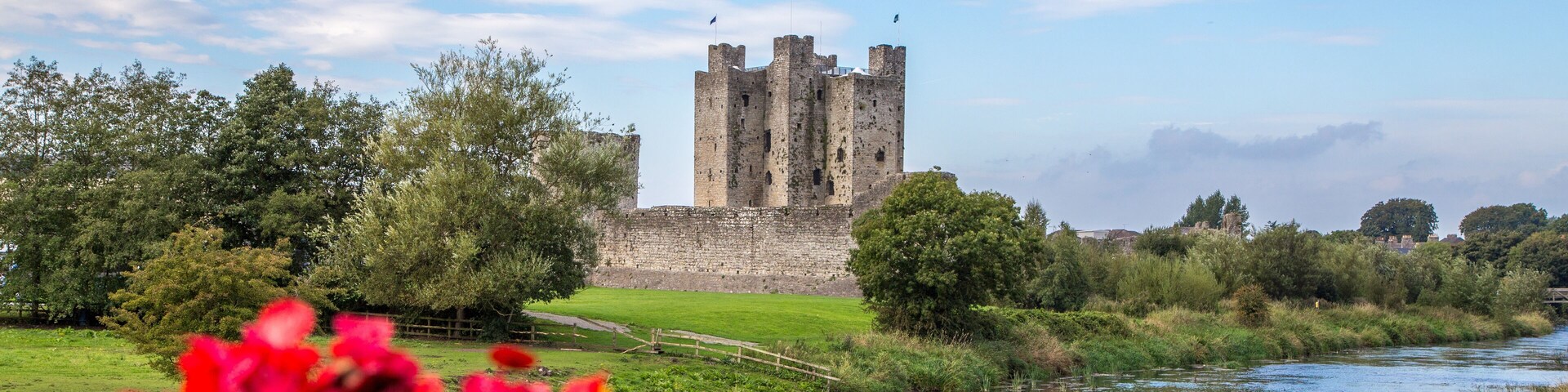 Um castelo rodeado por vegetação e um rio.