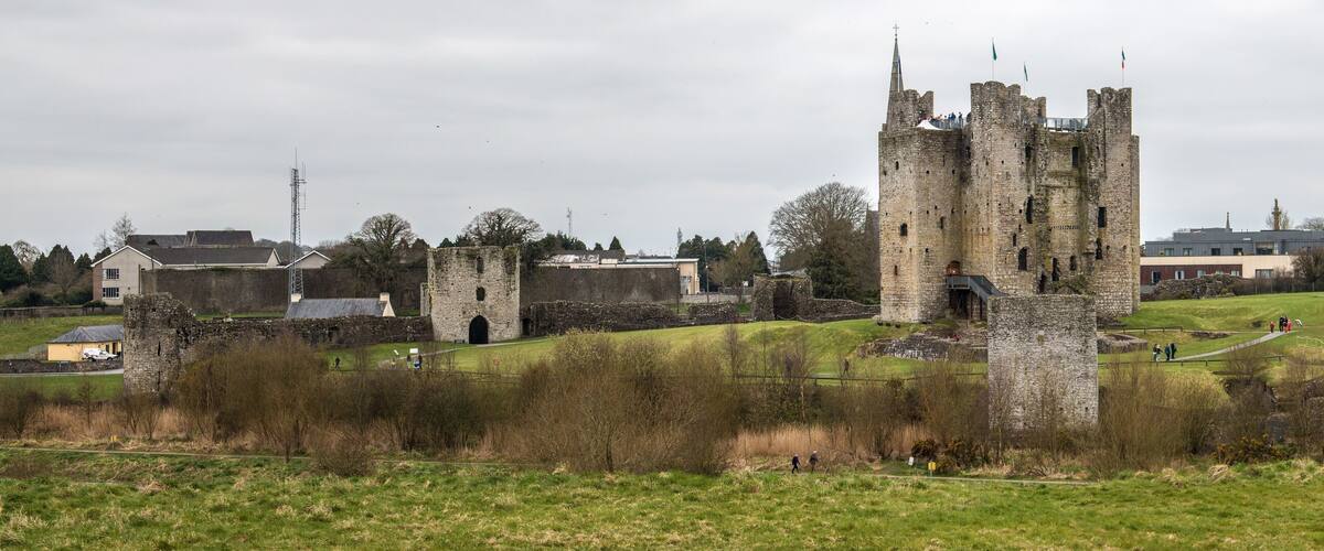 A historic castle with ruins and a modern building in the background.